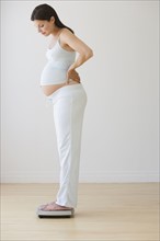 Pregnant woman standing on scale.