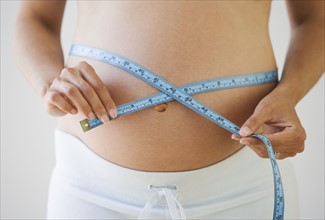 Pregnant woman measuring waist.