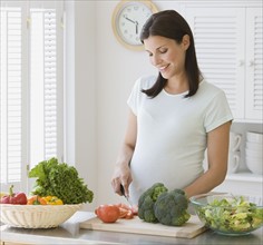 Pregnant woman chopping vegetables.