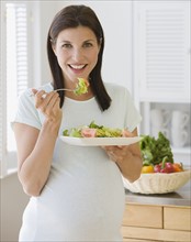 Pregnant woman eating salad.