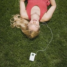 Woman listening to mp3 player in grass.