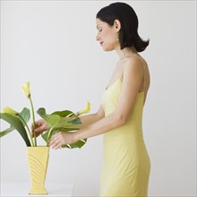 Woman arranging flowers in vase.