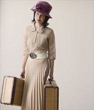 Woman in vintage clothing carrying suitcases.