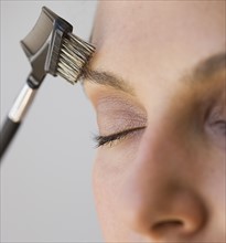 Woman brushing eyebrow.