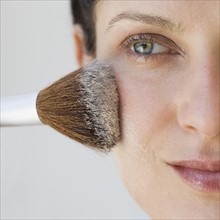 Woman applying make up with brush.