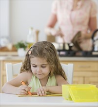Girl coloring at kitchen table.