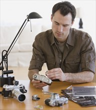 Man assembling camera at table.