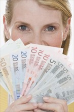 Woman holding fanned out Euro banknotes.
