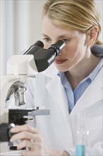 Female scientist looking into microscope.