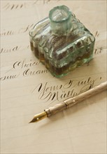 Quill pen and ink bottle on old letter.