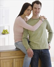 Couple hugging in kitchen.