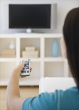 Woman pointing remote control at television.