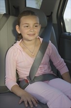 Girl sitting in backseat of car.