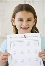Girl holding schoolwork with A plus grade .