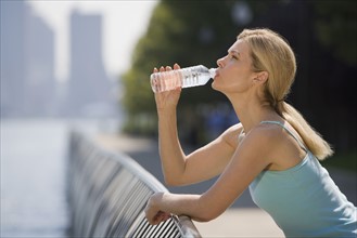 Woman drinking from water bottle.