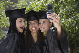 Female college graduates taking own photograph.