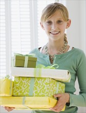Teenaged girl holding stack of gifts.