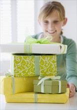 Teenaged girl behind stack of gifts.