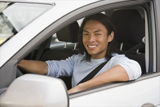 Asian man driving in car.