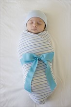 Baby wrapped in blanket with bow.