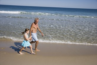 Father and daughter walking on beach.