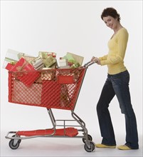 Woman pushing shopping cart of gifts.
