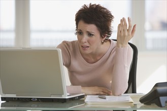 Frustrated businesswoman looking at laptop.