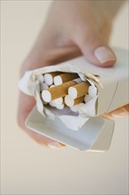 Woman holding open pack of cigarettes.