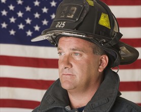 Male firefighter in front of American flag.