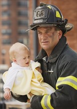 Male firefighter carrying baby.