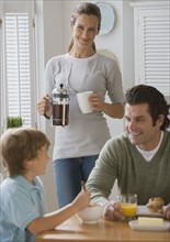 Mother smiling at father and son at breakfast table.