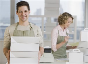 Male bakery worker carrying stack of boxes.