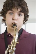 Teenaged boy playing saxophone.