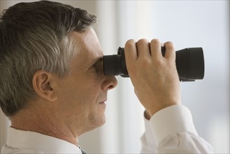 Businessman looking through binoculars.