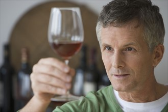 Man looking at glass of wine.