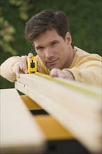 Man measuring piece of wood.