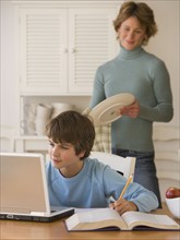 Boy doing homework with laptop.