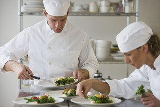 Male and female chefs plating food.