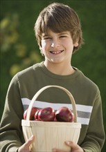 Boy holding basket of apples.
