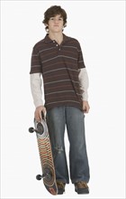 Teenaged boy holding skateboard.