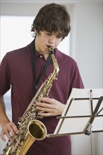Teenaged boy playing saxophone.