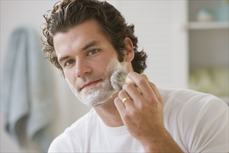 Man applying shaving cream to face.