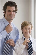 Father and son tying neckties.