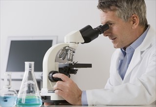 Male scientist looking in microscope.
