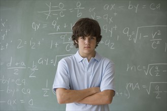 Teenaged boy in front of blackboard with math equations.