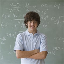Teenaged boy in front of blackboard with math equations.