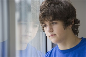 Teenaged boy looking out window.