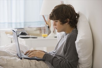 Teenaged boy typing on laptop.