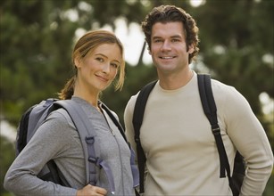 Couple wearing backpacks in woods.