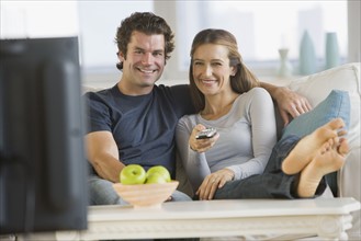 Couple watching television on sofa.